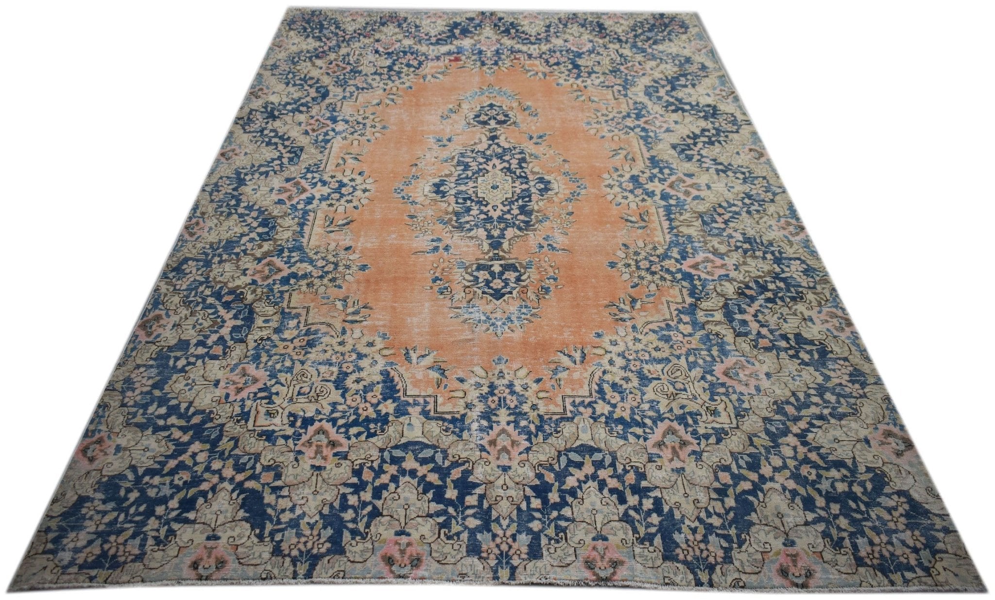A vintage Persian Kerman rug featuring a central medallion and intricate floral patterns in blue and orange.