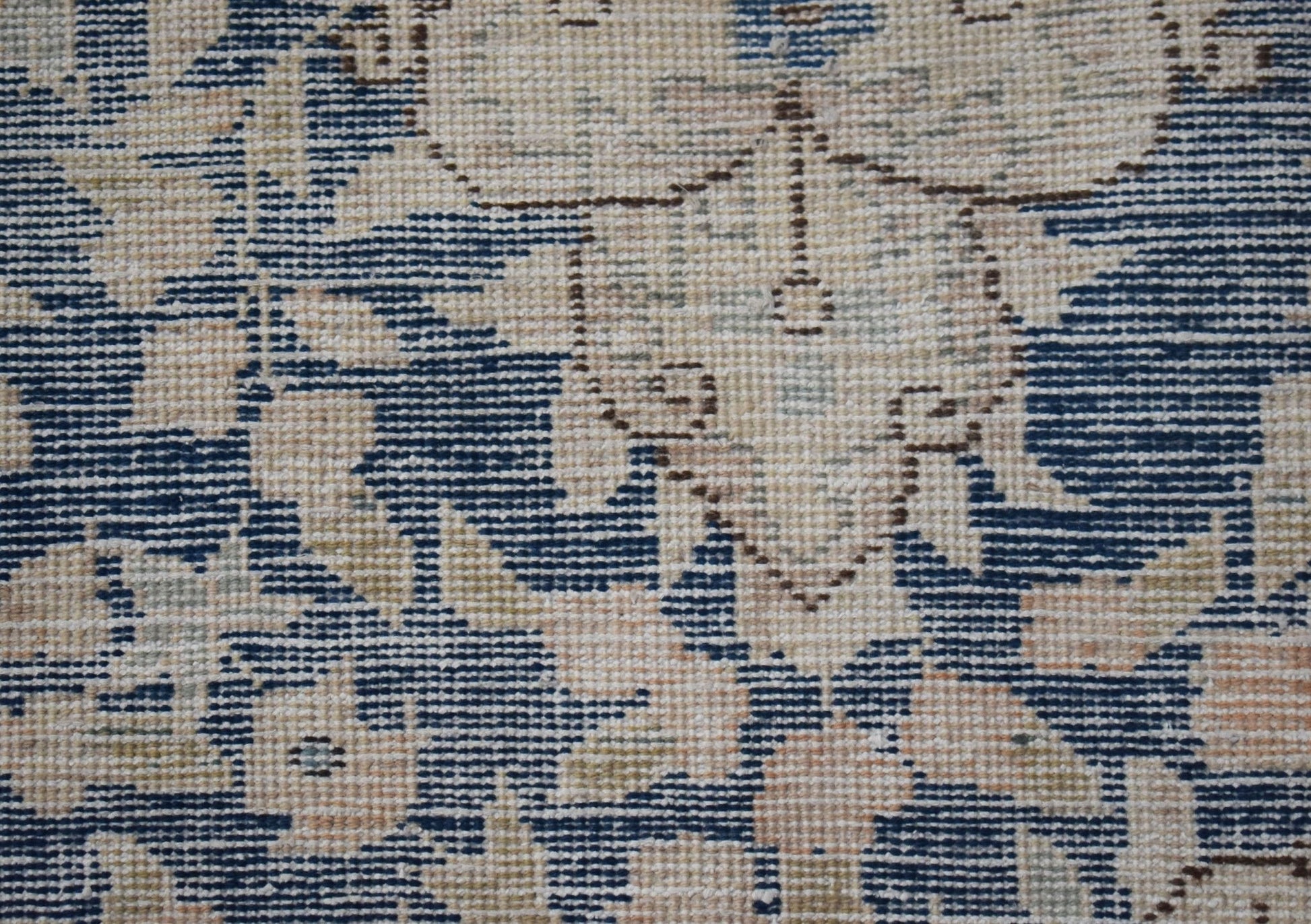 A close-up of a vintage Persian Kerman rug featuring intricate floral patterns in blue and cream.