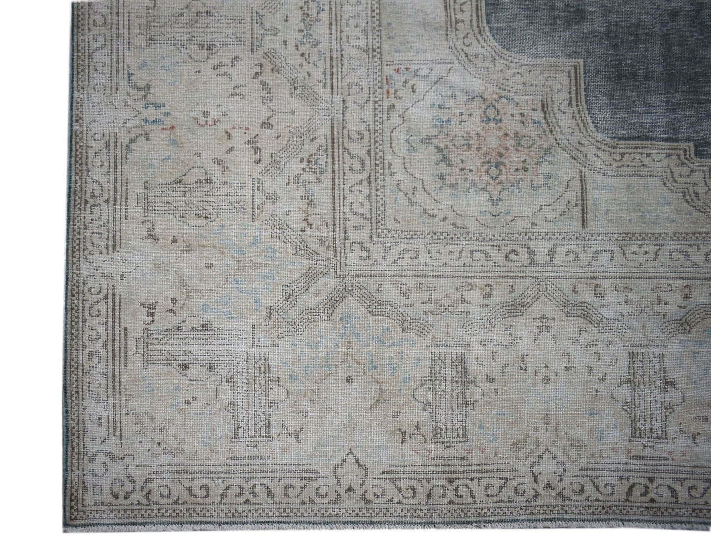 A vintage Persian Kerman rug featuring a faded floral medallion pattern in neutral tones.