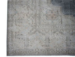 A vintage Persian Kerman rug featuring a faded floral medallion pattern in neutral tones.