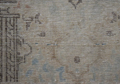 A close-up view of a vintage Persian Kerman rug featuring intricate, faded floral patterns.