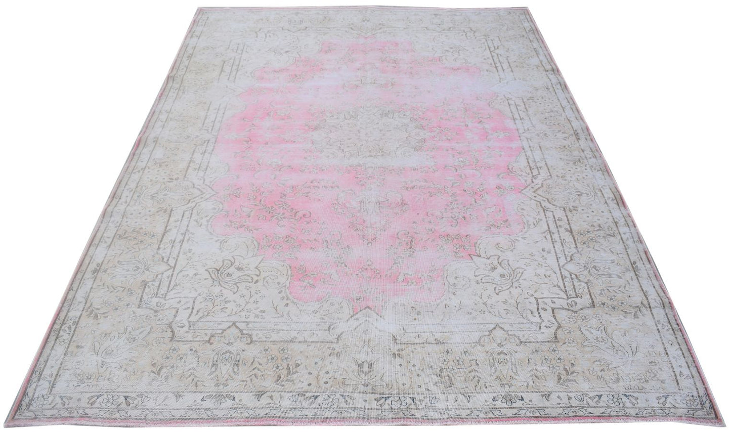 A vintage Persian Kerman rug featuring a central pink medallion and intricate floral patterns.