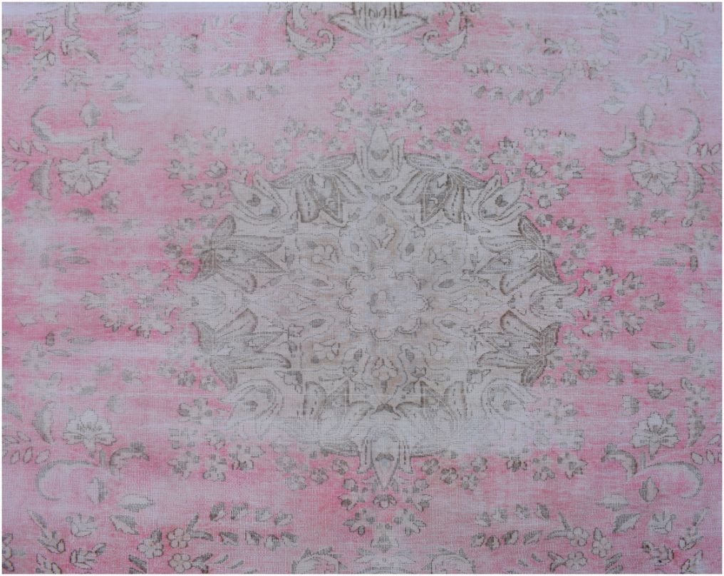 A vintage Persian Kerman rug featuring a central floral medallion in soft pink and beige tones.