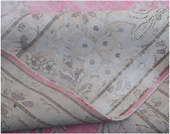 A vintage Persian Kerman rug featuring a faded floral pattern in soft pink and neutral tones.
