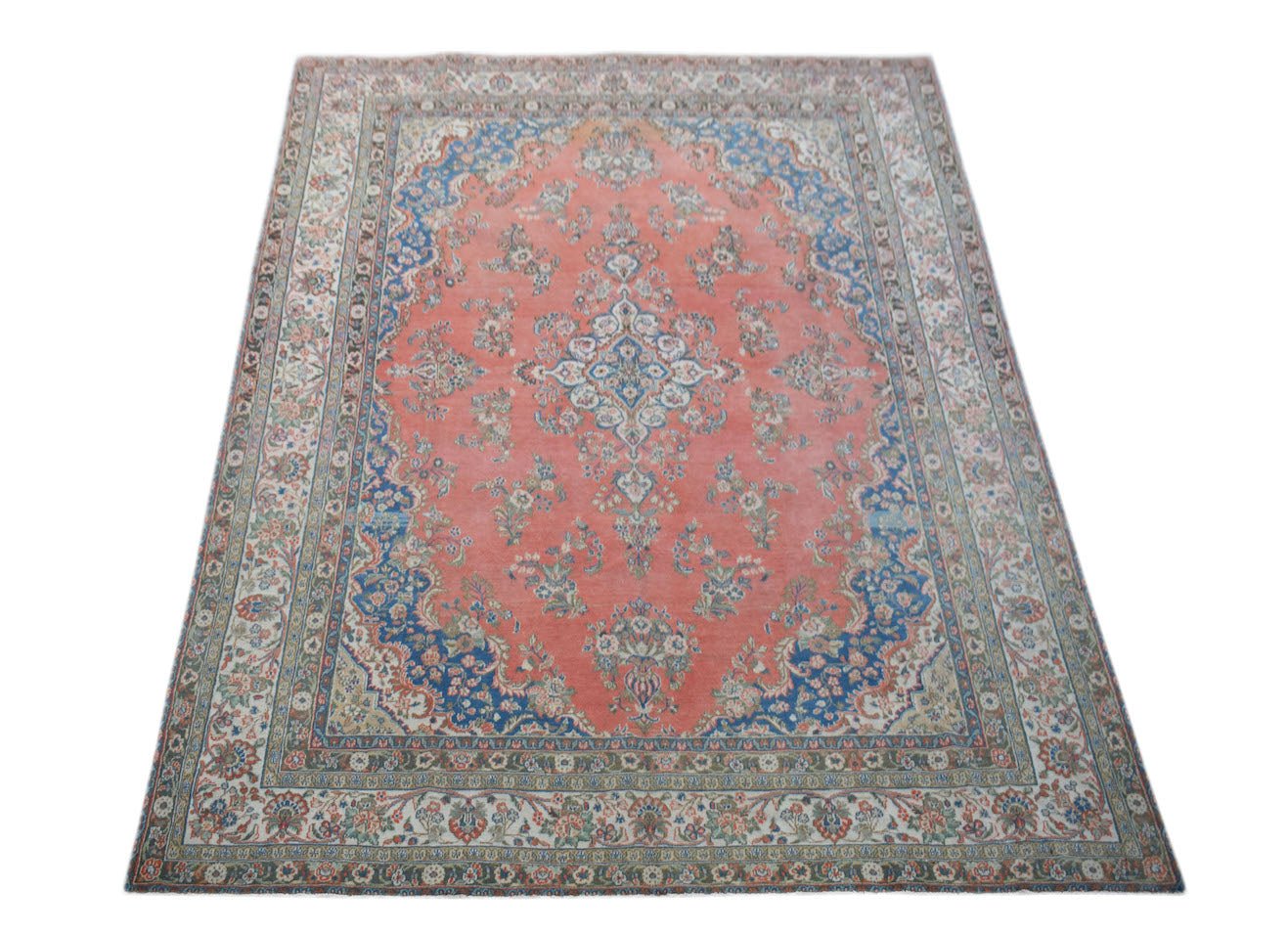 A vintage Persian Kerman rug featuring a central medallion and intricate floral patterns in coral.