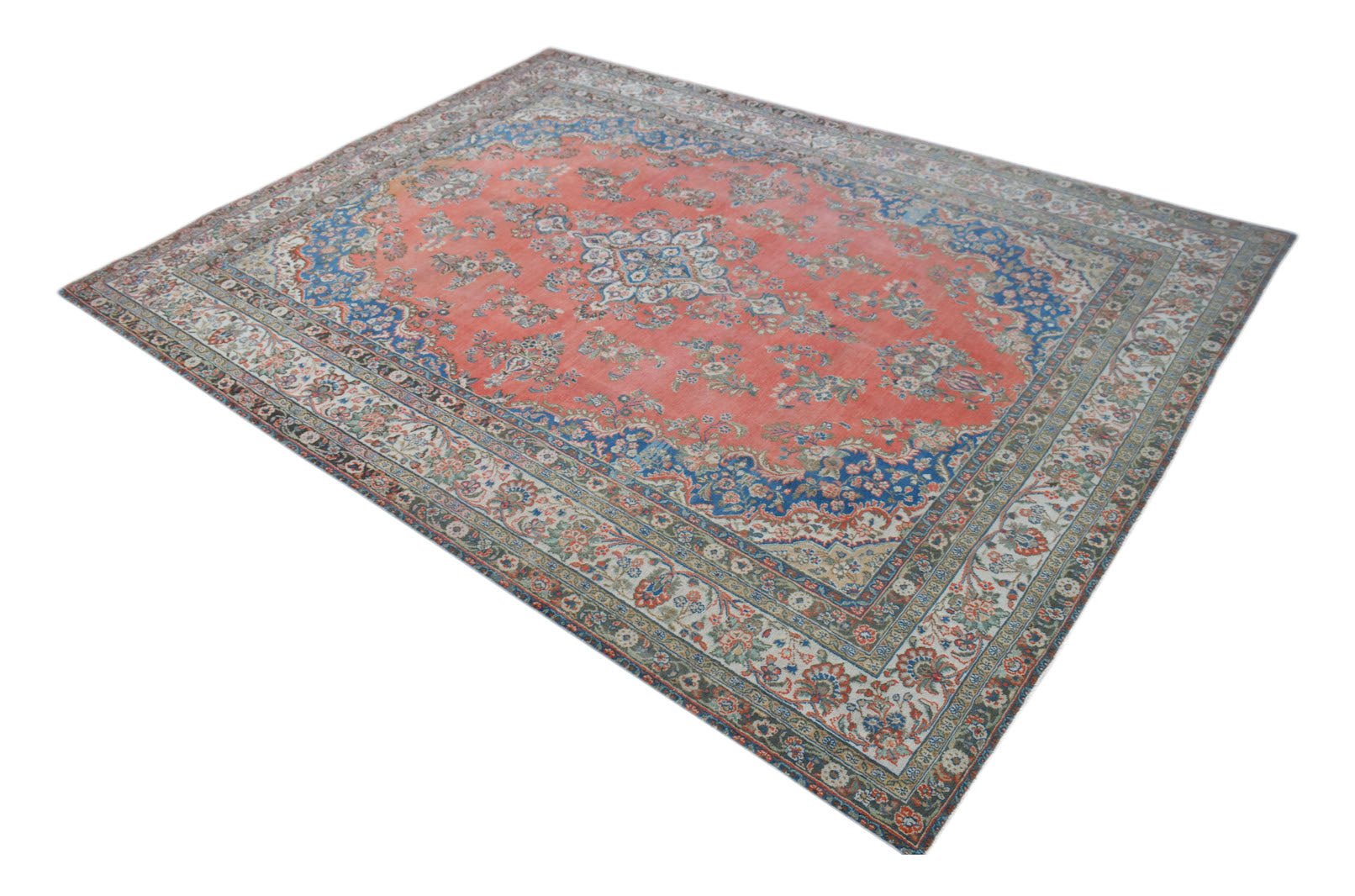 A vintage Persian Kerman rug featuring a central medallion and intricate floral patterns in red.