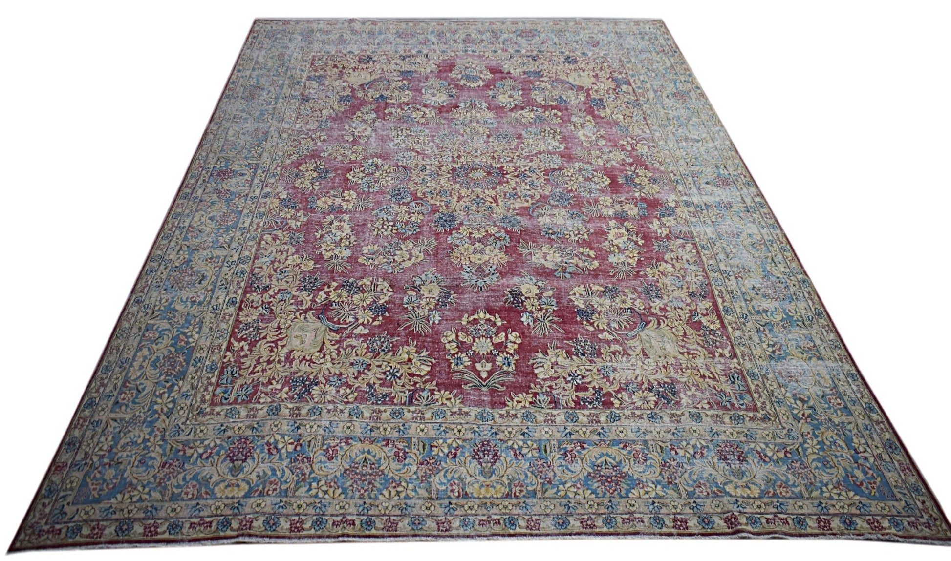 A vintage Persian Kerman rug featuring an intricate floral medallion design in red and blue tones.