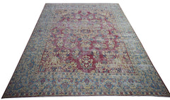 A vintage Persian Kerman rug featuring an intricate floral medallion design in red and blue tones.