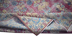 A vintage Persian Kerman rug featuring a deep red field with intricate floral patterns and a blue border.