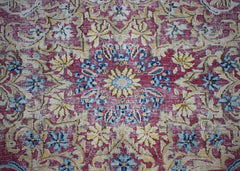 A vintage Persian Kerman rug featuring an intricate floral medallion in red, blue, and cream.