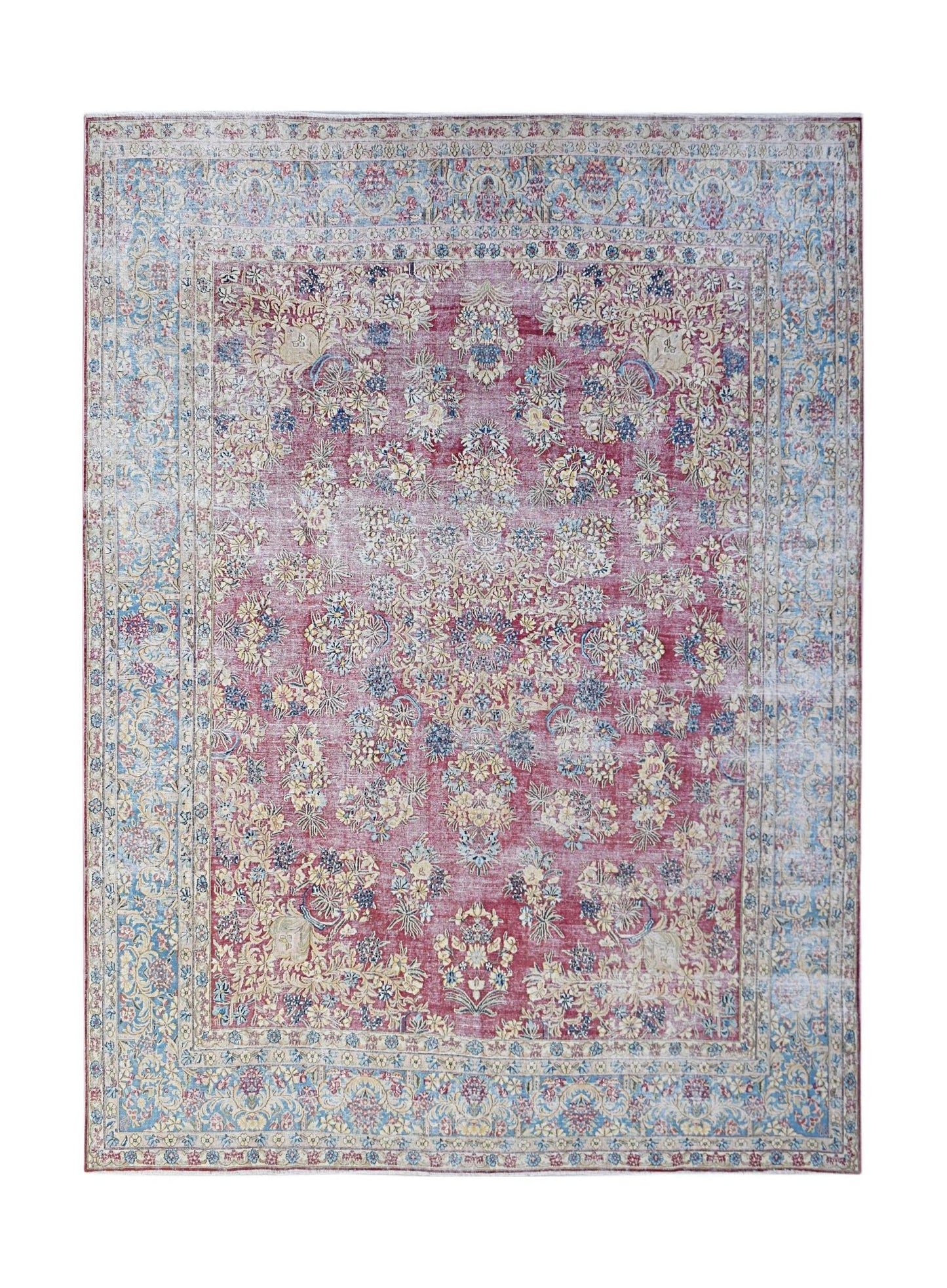 A vintage Persian Kerman rug featuring a central floral medallion on a red field with blue borders.