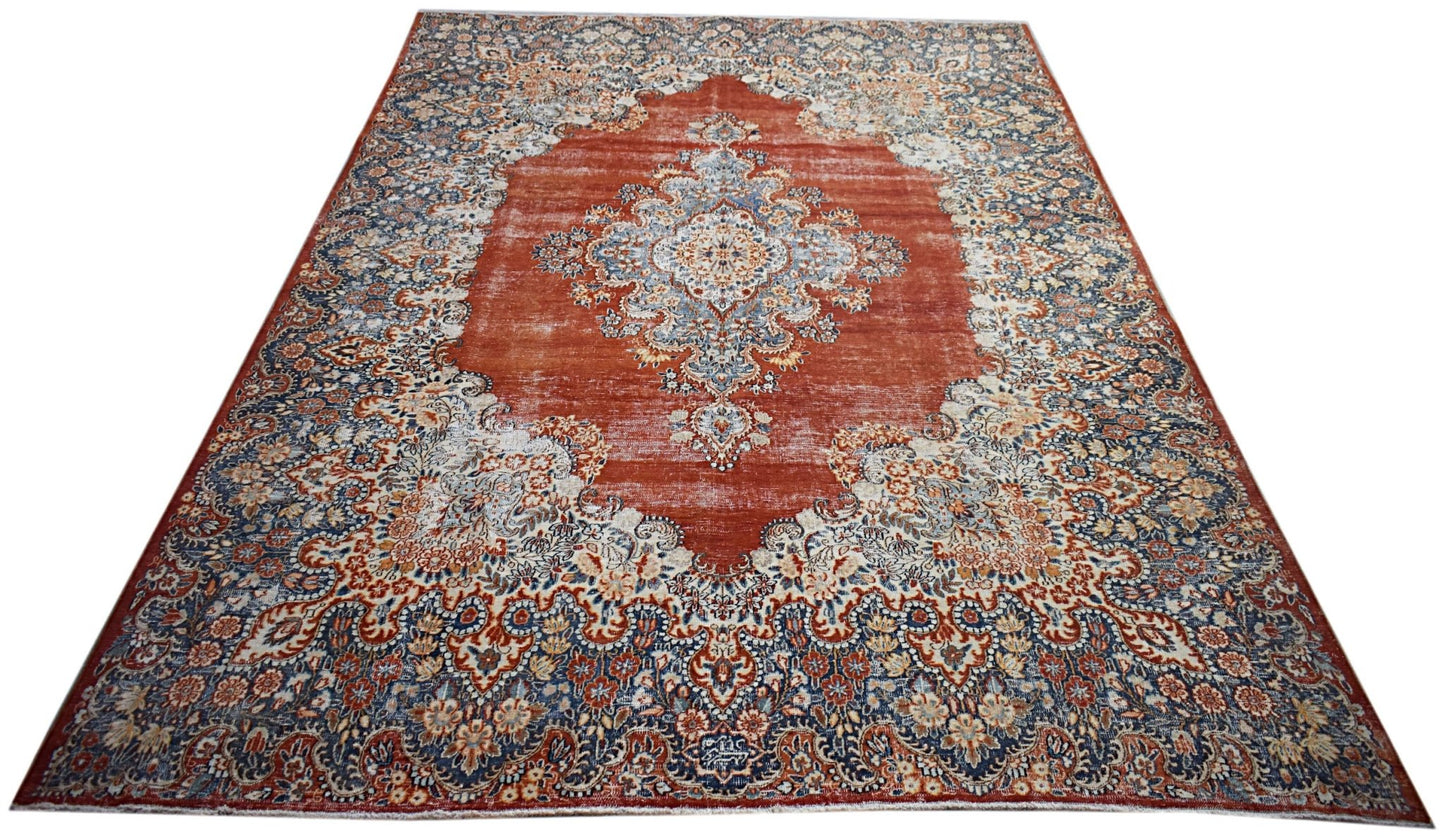 A vintage Persian Kerman rug featuring a central medallion and intricate floral patterns in red.