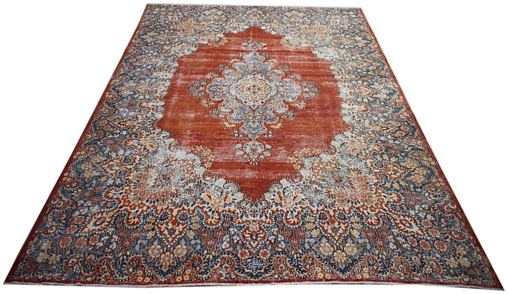 A vintage Persian Kerman rug featuring a central medallion and intricate floral patterns in red.