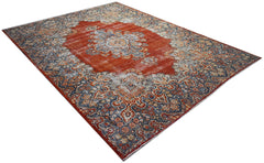 A vintage Persian Kerman rug featuring a central medallion and intricate floral patterns in red.
