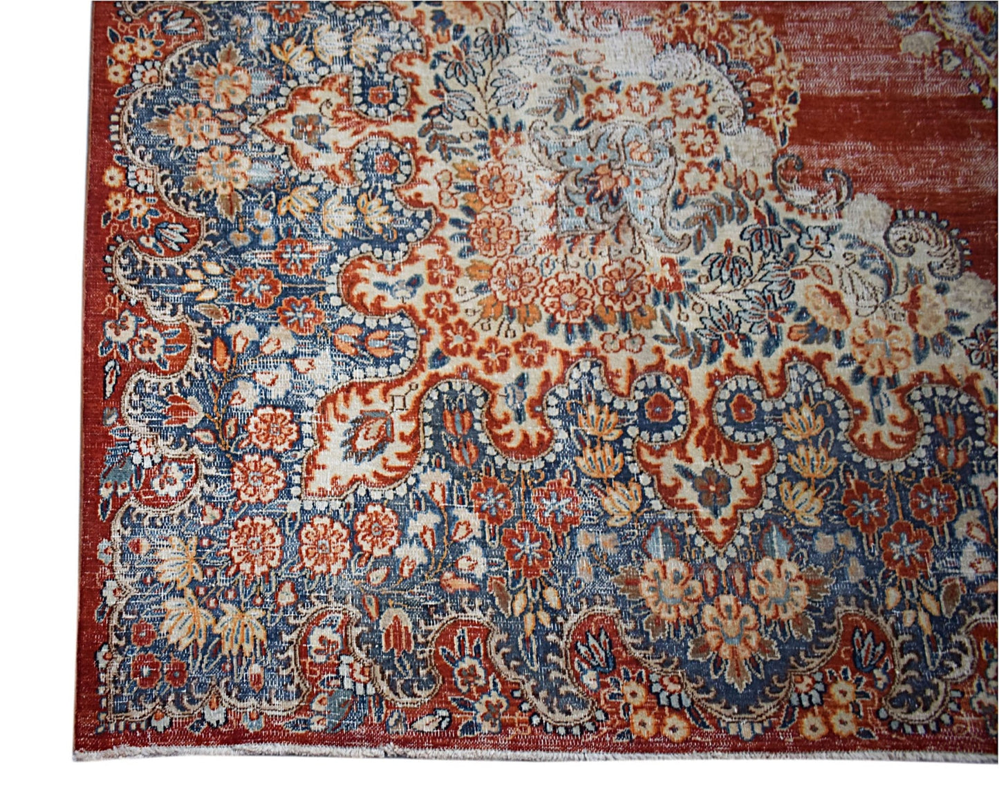 A vintage Persian Kerman rug featuring an intricate floral pattern in shades of red and blue.