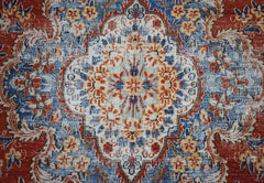 A vintage Persian Kerman rug featuring a central floral medallion in blue, red, and cream tones.