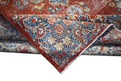 A vintage Persian Kerman rug featuring a detailed floral medallion in shades of red and blue.