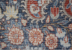 A close-up of a vintage Persian Kerman rug featuring intricate floral patterns in red and blue.