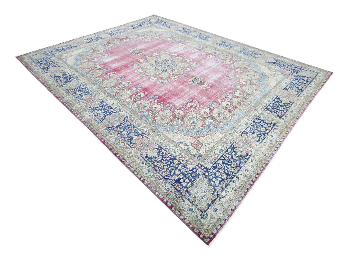 Vintage hand-knotted Persian Kerman rug with a pink floral field, central medallion, and ornate blue border.