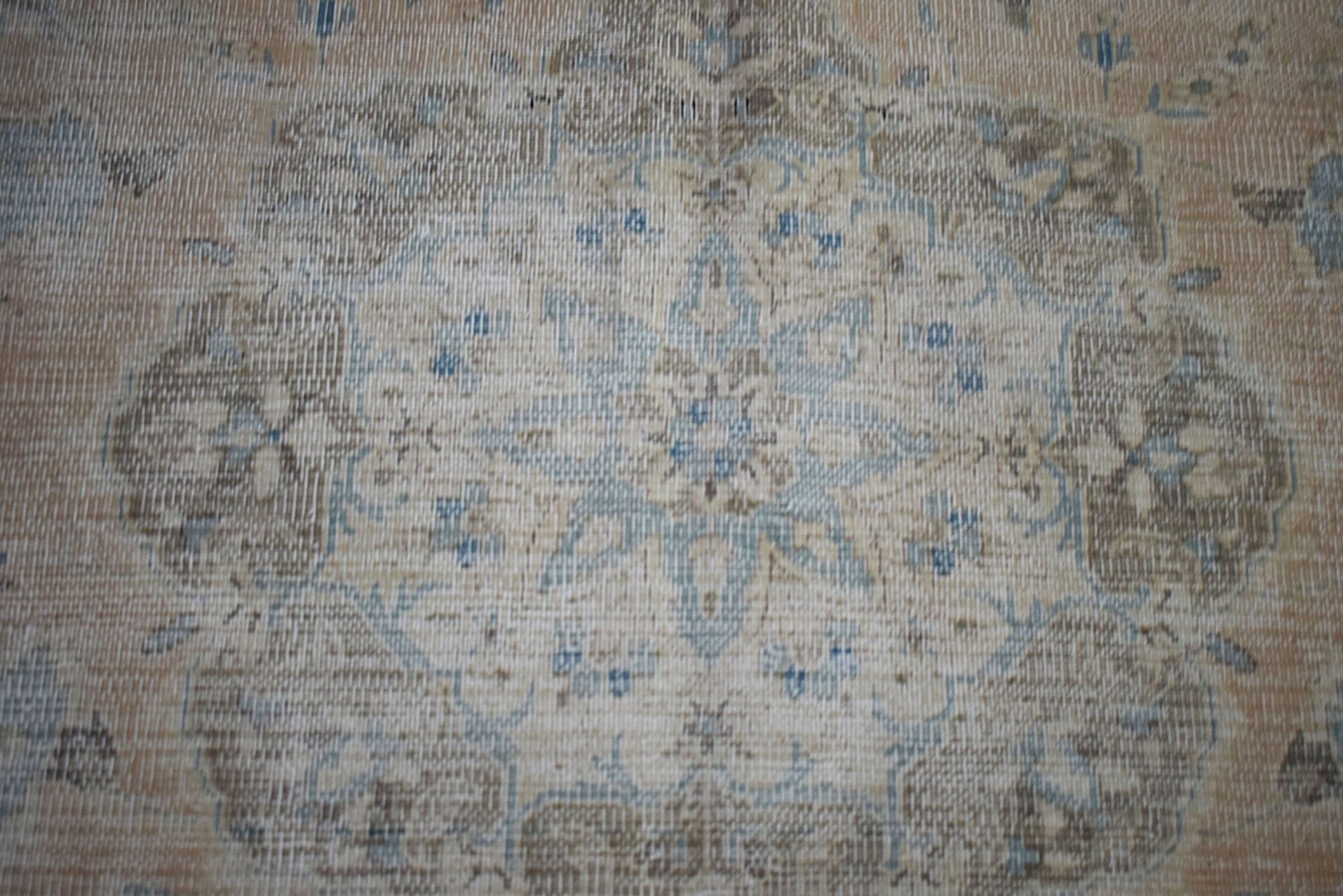 A vintage Persian Kerman rug featuring a central floral medallion in soft blue and beige tones.