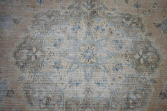A vintage Persian Kerman rug featuring a central floral medallion in soft blue and beige tones.