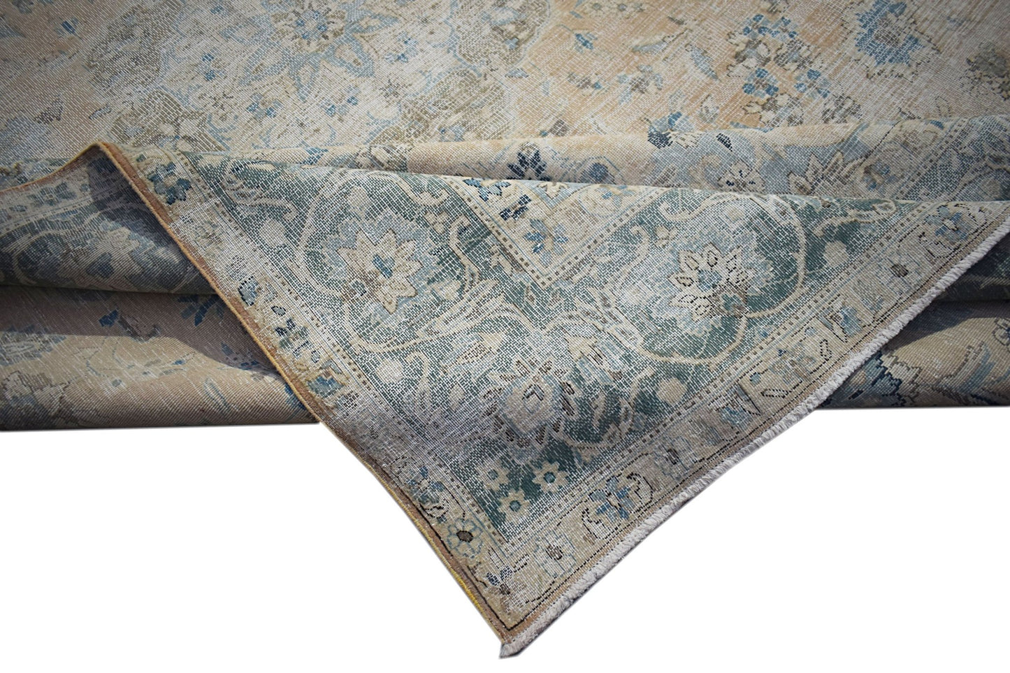 A vintage Persian Kerman rug featuring a faded floral medallion design in blue and beige tones.
