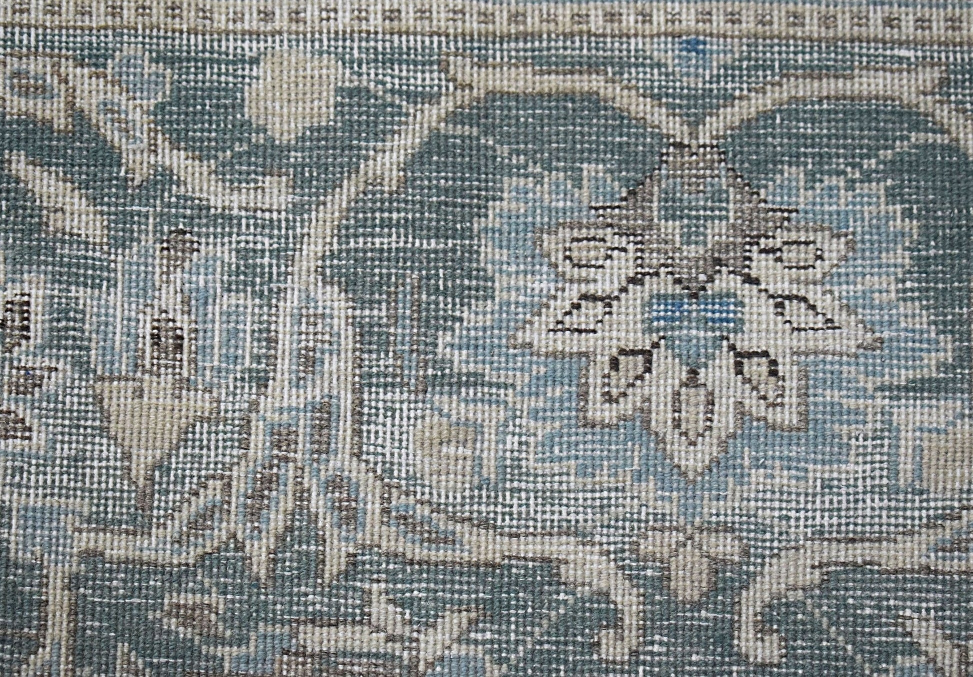 A close-up of a vintage Persian Kerman rug featuring intricate blue and beige floral patterns.