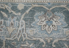 A close-up of a vintage Persian Kerman rug featuring intricate blue and beige floral patterns.