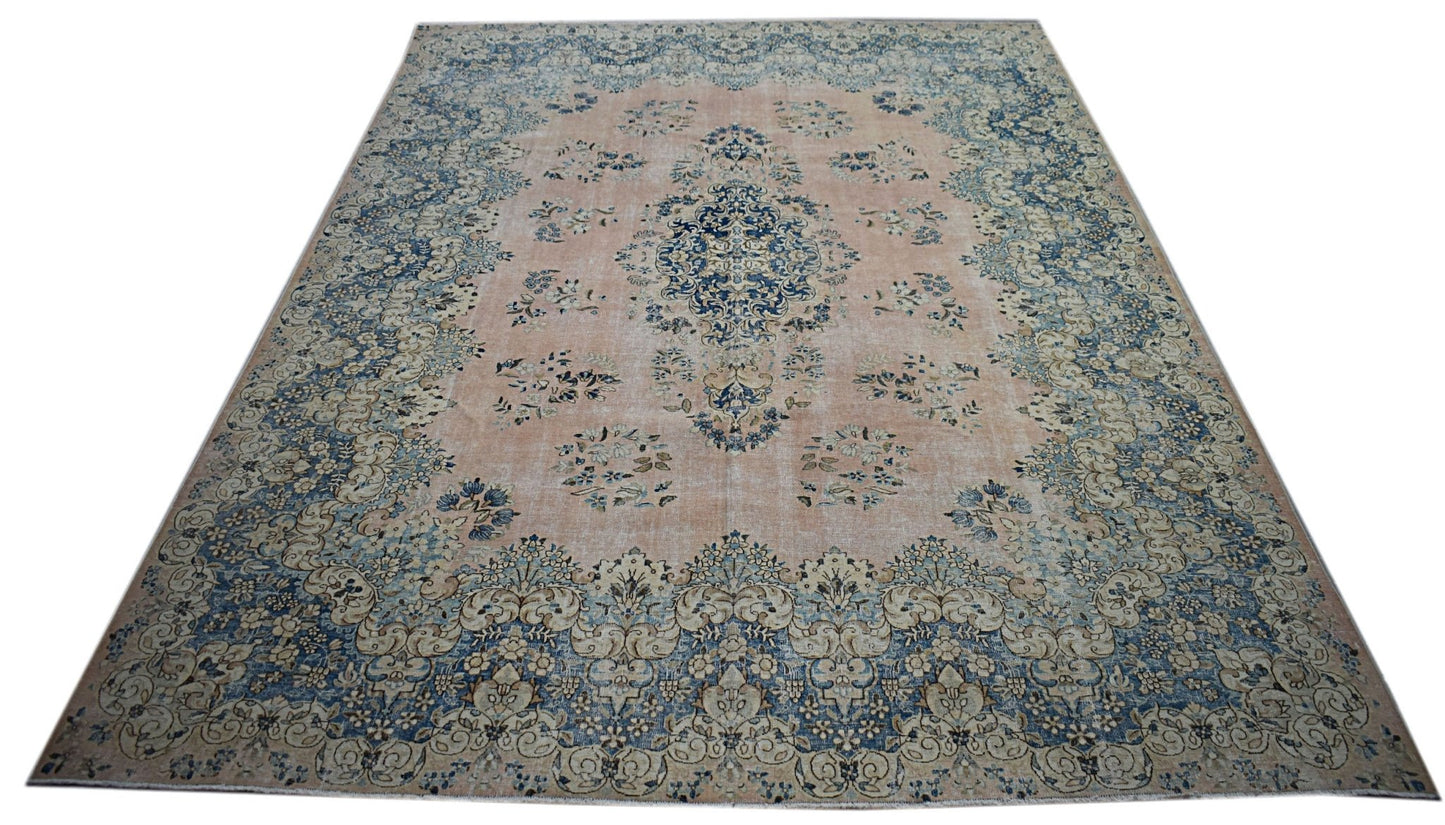 A vintage Persian Kerman rug featuring a central medallion and floral motifs in blue and peach.