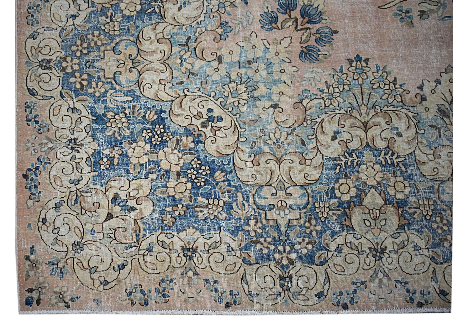 A vintage Persian Kerman rug featuring intricate floral patterns in blue and beige tones.