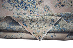 A vintage Persian Kerman rug featuring a soft pink background with intricate blue floral patterns.
