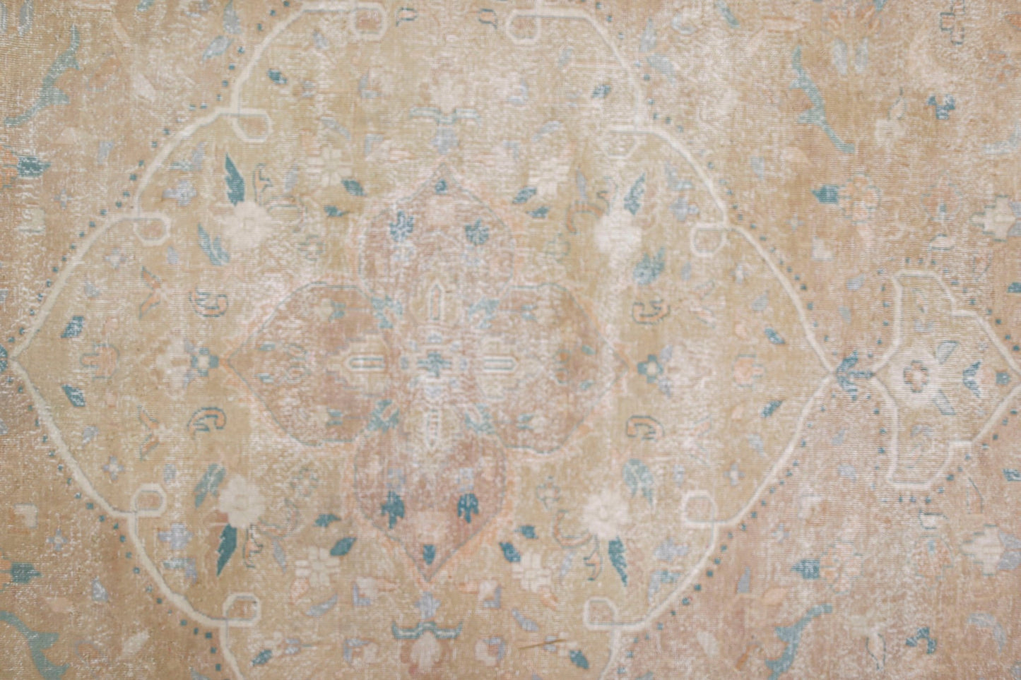 A vintage Persian Kerman rug featuring a central medallion with intricate floral motifs in soft tones.