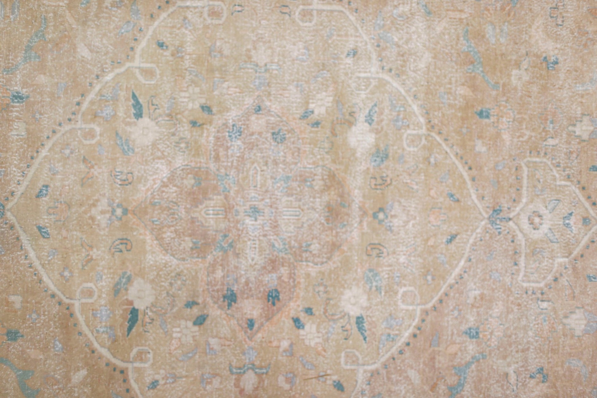 A vintage Persian Kerman rug featuring a central medallion with intricate floral motifs in soft tones.