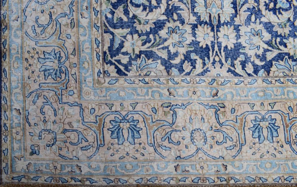 A vintage Persian Kerman rug featuring intricate floral patterns in shades of blue and beige.