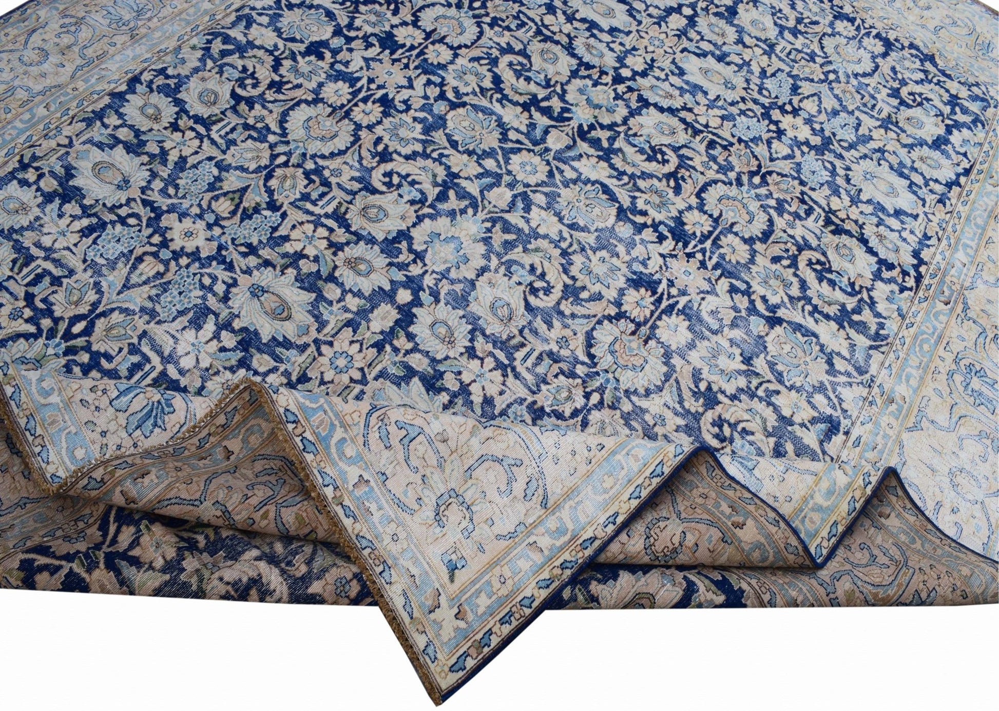 A vintage Persian Kerman rug featuring an intricate blue and cream floral pattern.