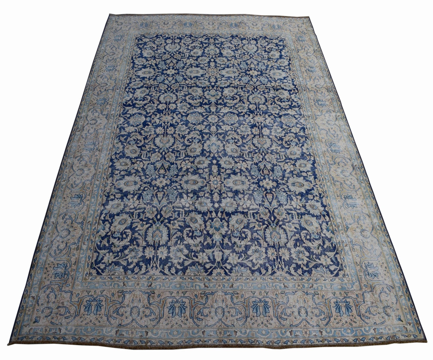 A vintage Persian Kerman rug featuring an intricate blue and cream floral pattern.