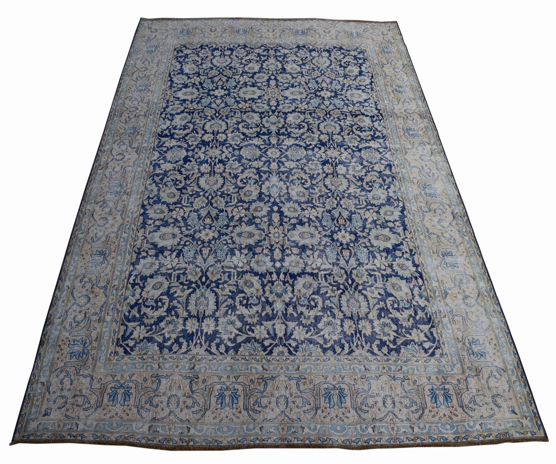 A vintage Persian Kerman rug featuring an intricate blue and cream floral pattern.