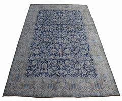 A vintage Persian Kerman rug featuring an intricate blue and cream floral pattern.