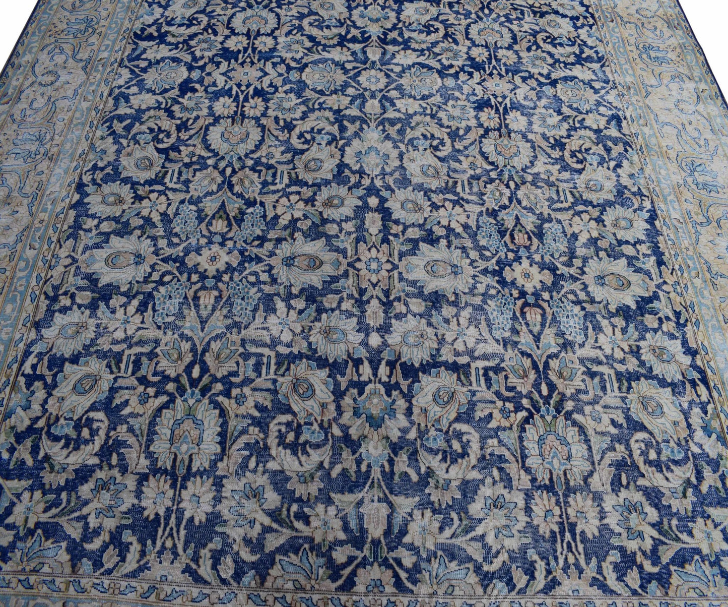A vintage Persian Kerman rug featuring an intricate blue and cream floral pattern.