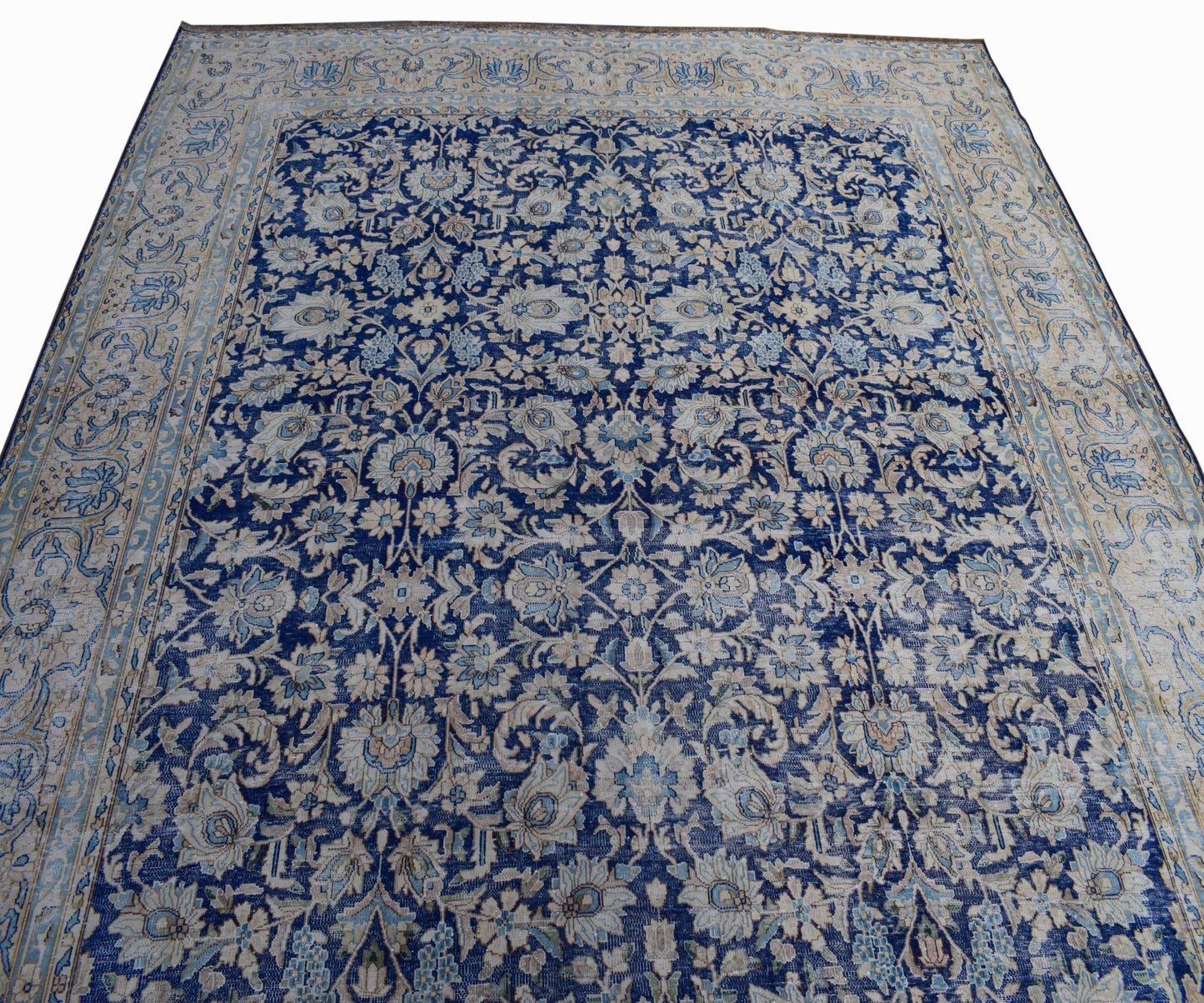 A vintage Persian Kerman rug featuring an intricate floral pattern in shades of blue and cream.