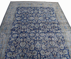 A vintage Persian Kerman rug featuring an intricate floral pattern in shades of blue and cream.