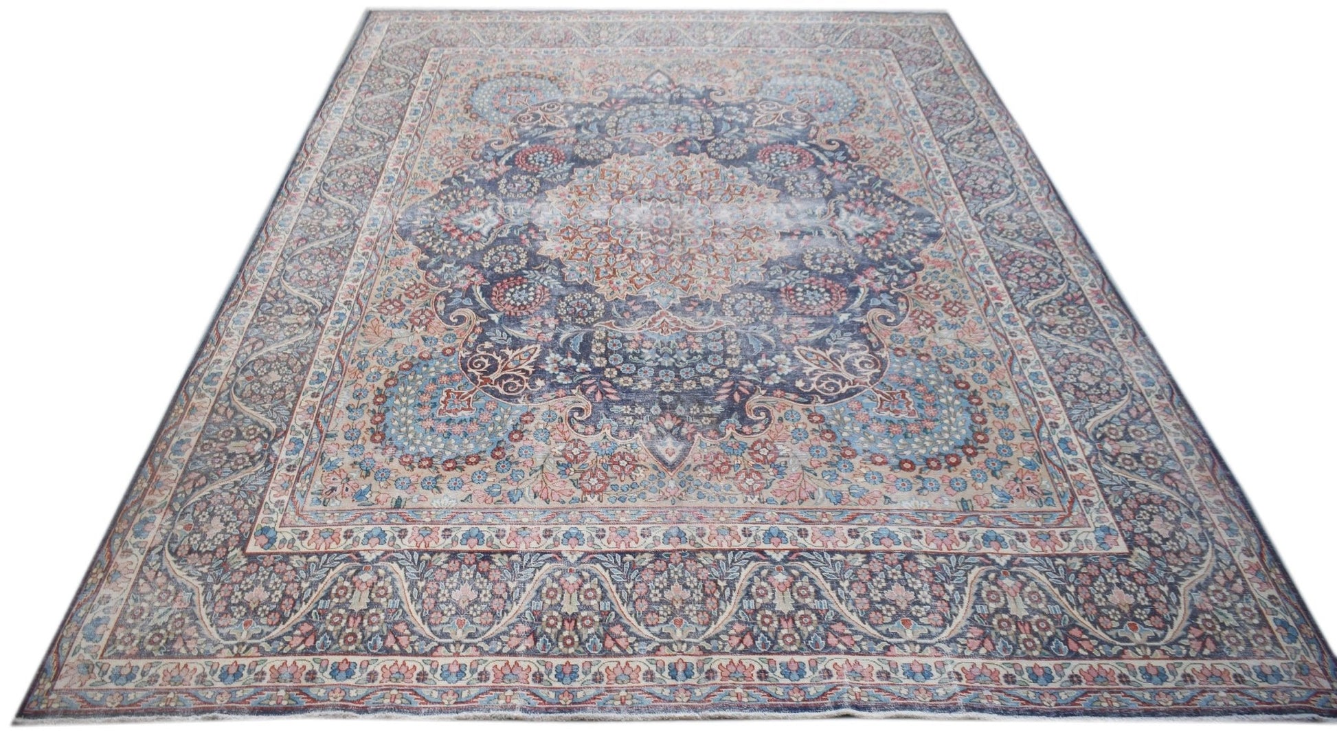 A vintage Persian Kerman rug featuring an intricate floral medallion design in blue and pink tones.