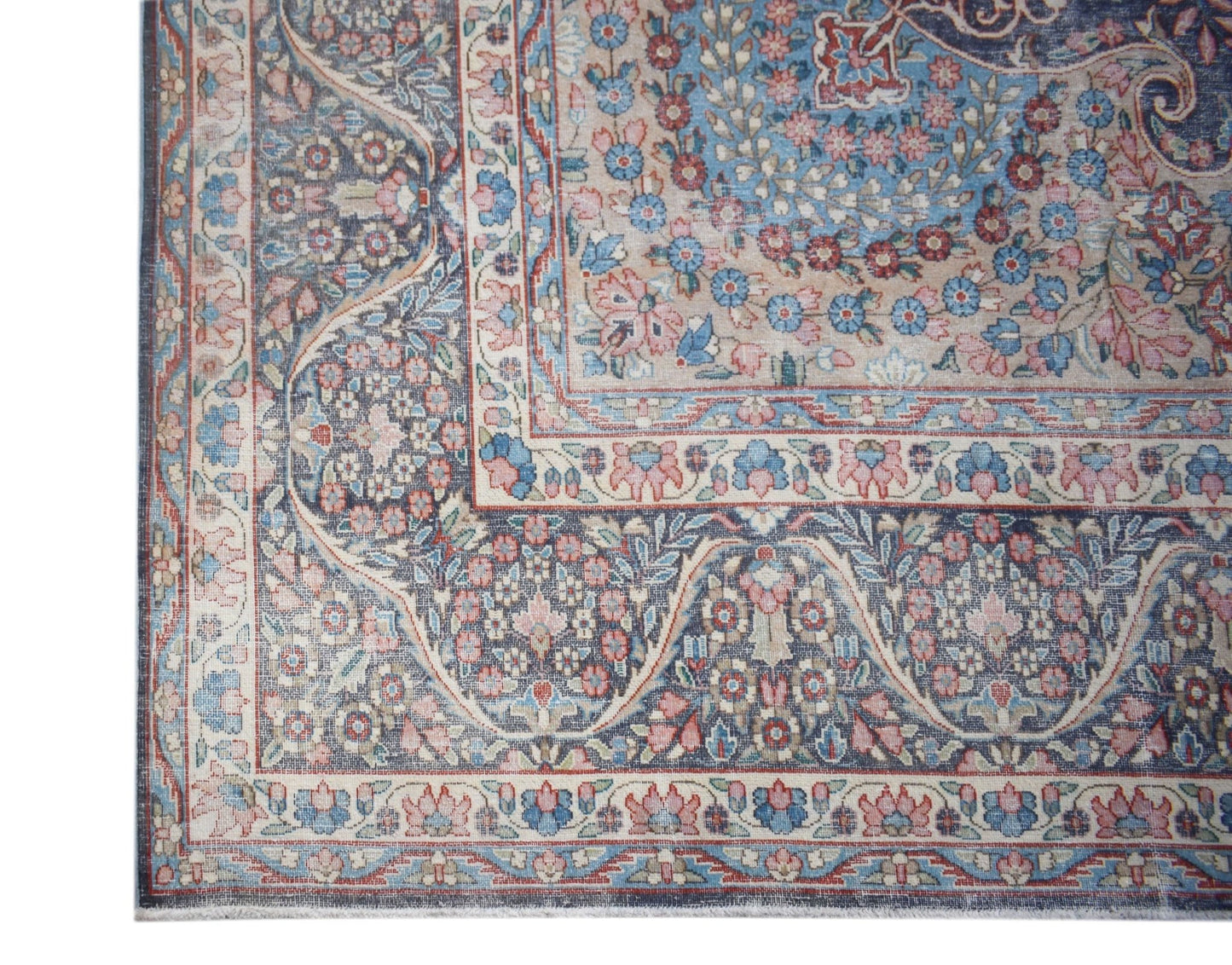 A vintage Persian Kerman rug featuring an intricate floral pattern in soft blue and pink tones.