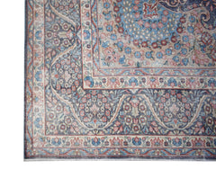 A vintage Persian Kerman rug featuring an intricate floral pattern in soft blue and pink tones.