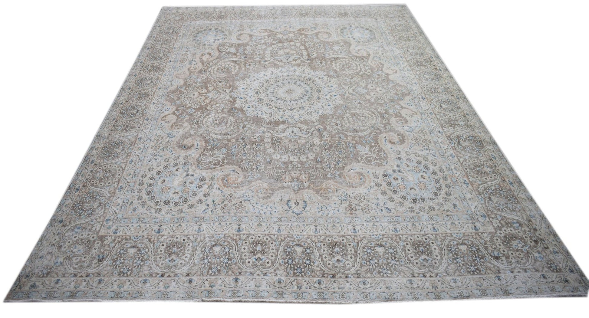 A vintage Persian Kerman rug featuring an intricate floral medallion in soft beige and blue tones.