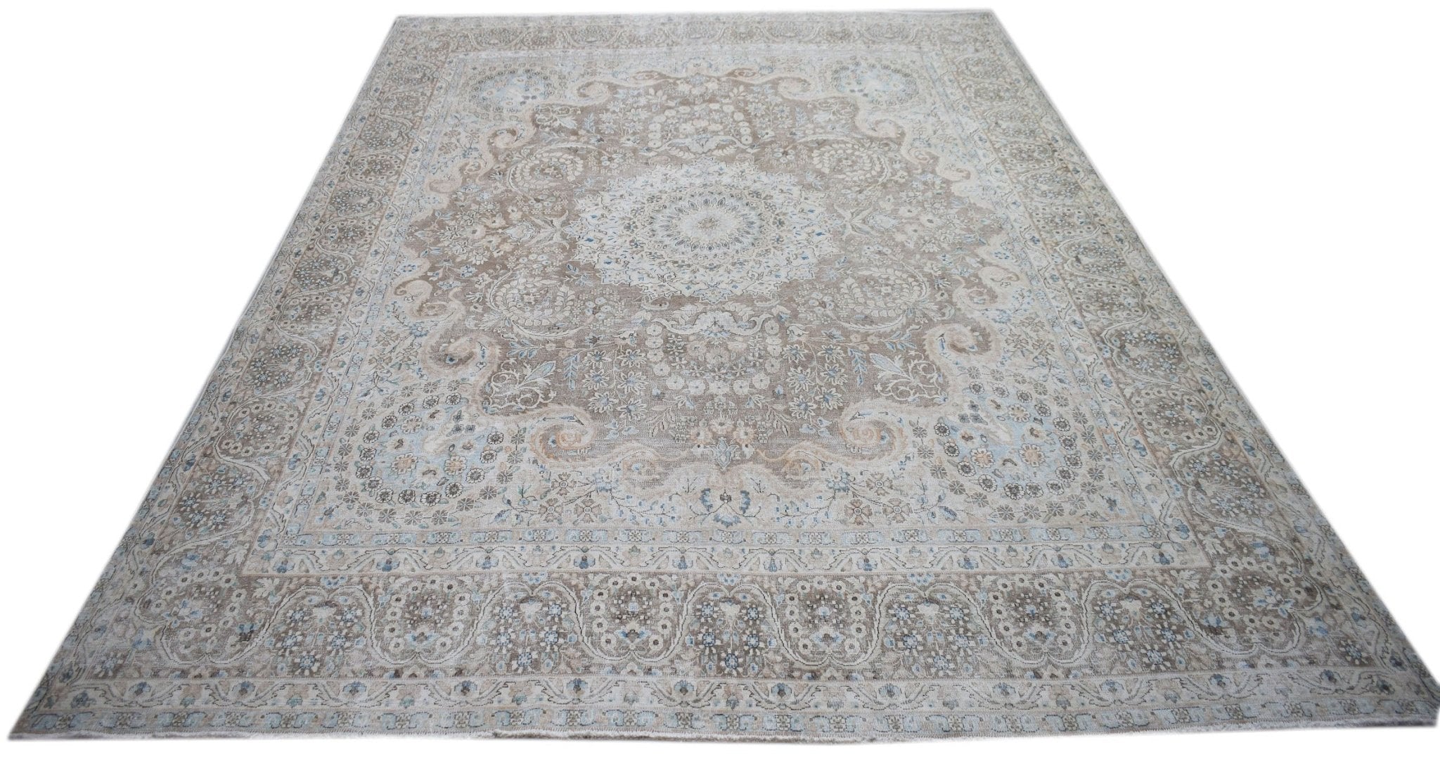 A vintage Persian Kerman rug featuring an intricate floral medallion in soft beige and blue tones.