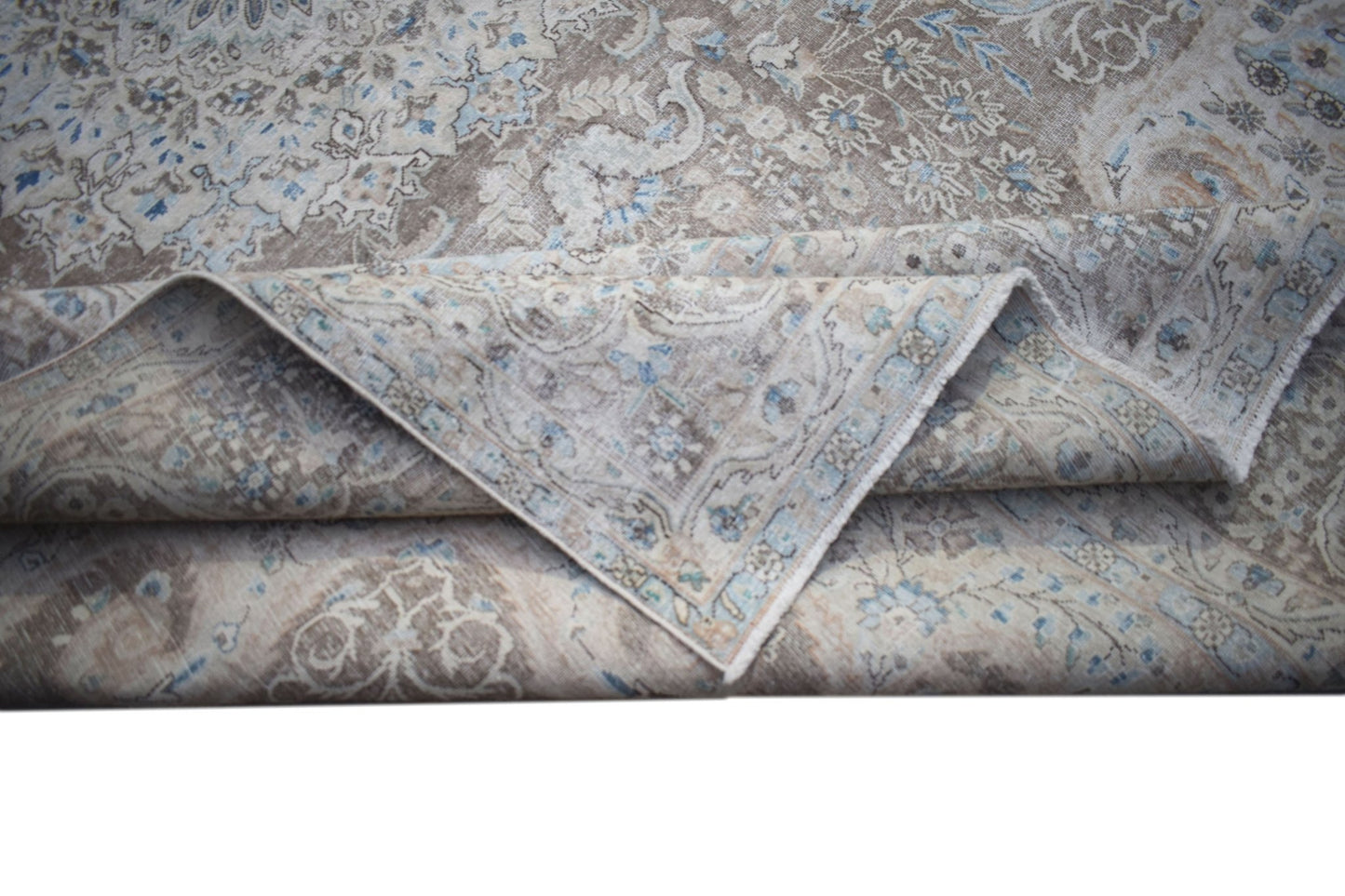 A vintage Persian Kerman rug featuring a detailed floral medallion pattern in soft blue and beige.
