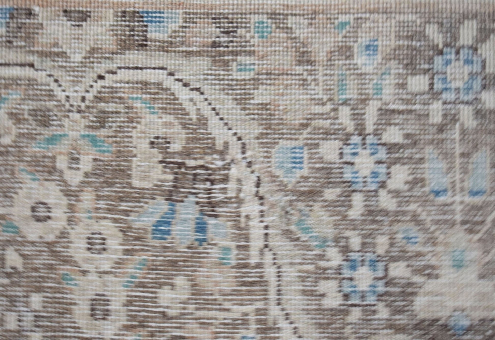 A close-up of a vintage Persian Kerman rug featuring intricate floral patterns in muted tones.