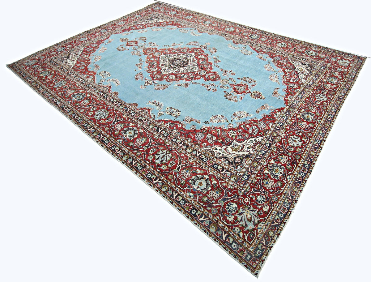 Vintage Persian Kerman wool rug with a light blue field, central medallion, and intricate red floral borders.