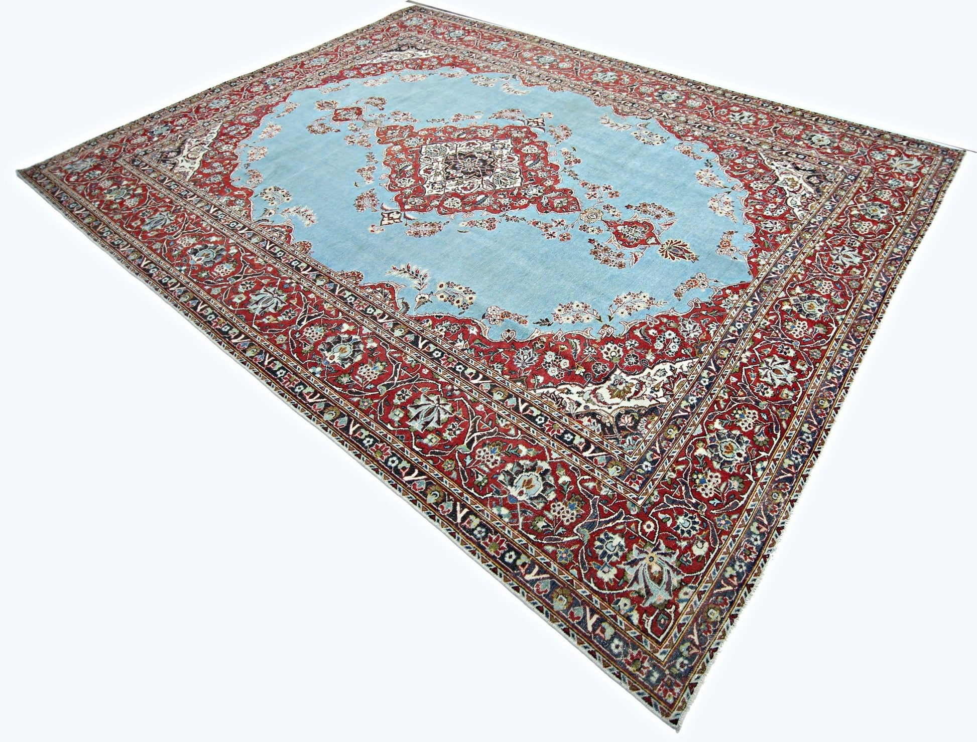 A vintage Persian Kerman rug featuring a central medallion on a light blue field with floral borders.